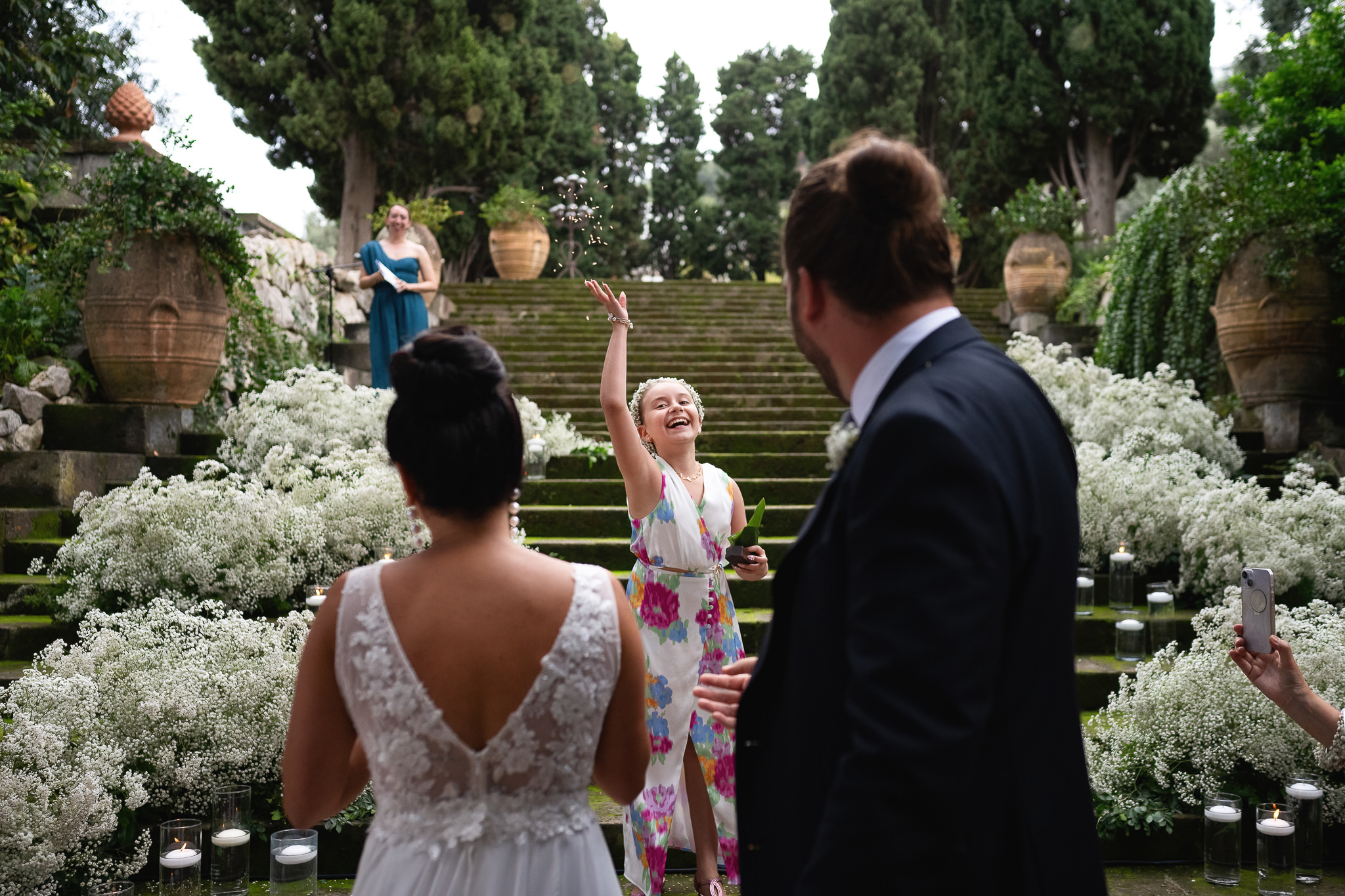 flower girl throwing flowers to bride and groom
