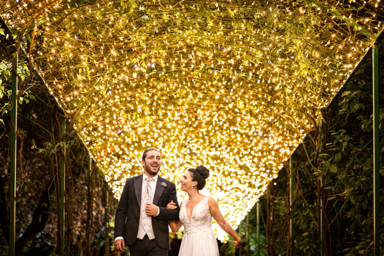 bride and groom walking under a fairy tale tunnel light in Villa Zagara