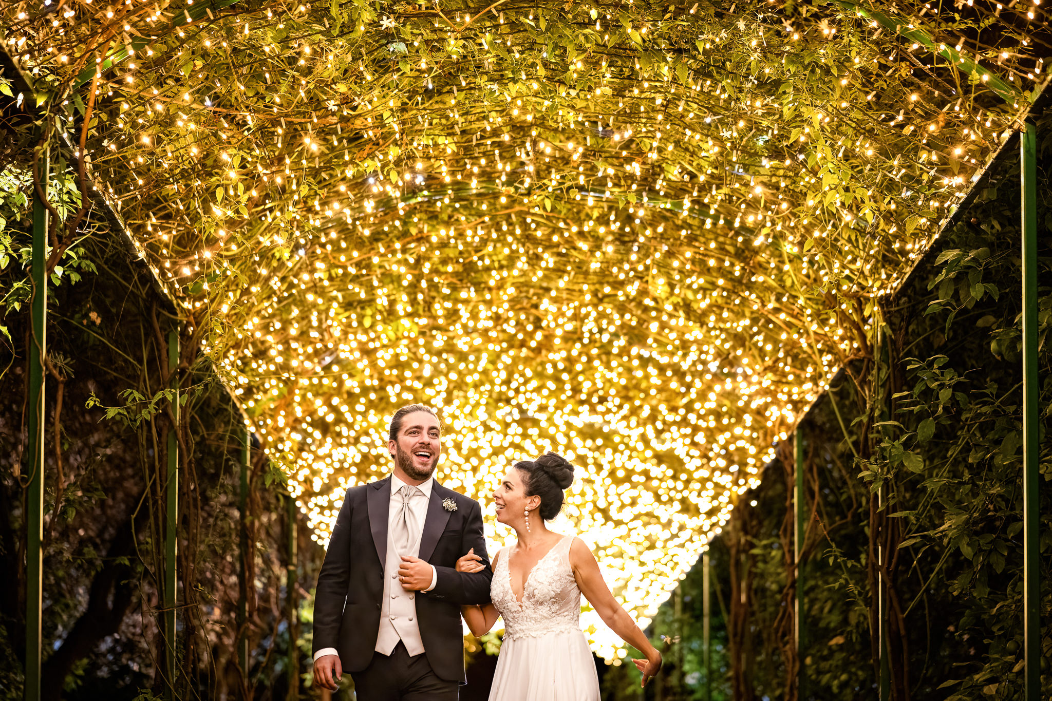 bride and groom walking under a fairy tale tunnel light in Villa Zagara 